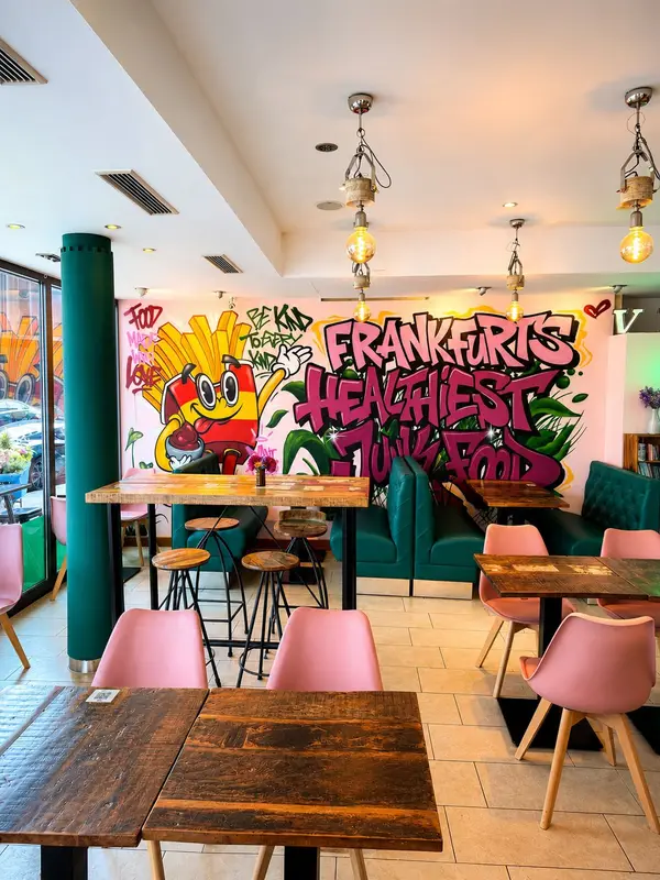 Dominion Food Revolution – Gastraum Gesamtansicht mit pinken Stühlen und türkisen Sofas