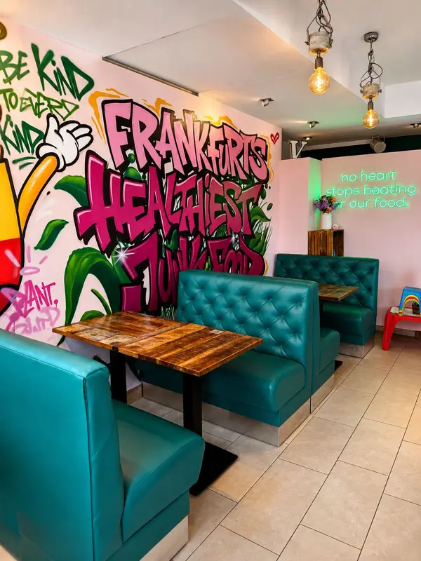 Dominion Food Revolution – Sitzbereich mit teal Sofas und Neon-Schriftzug